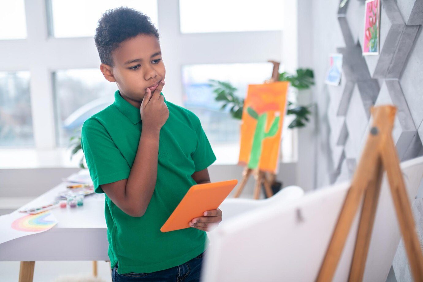 boy-with-tablet-looking-thoughtfully-drawing-easel_259150-59536